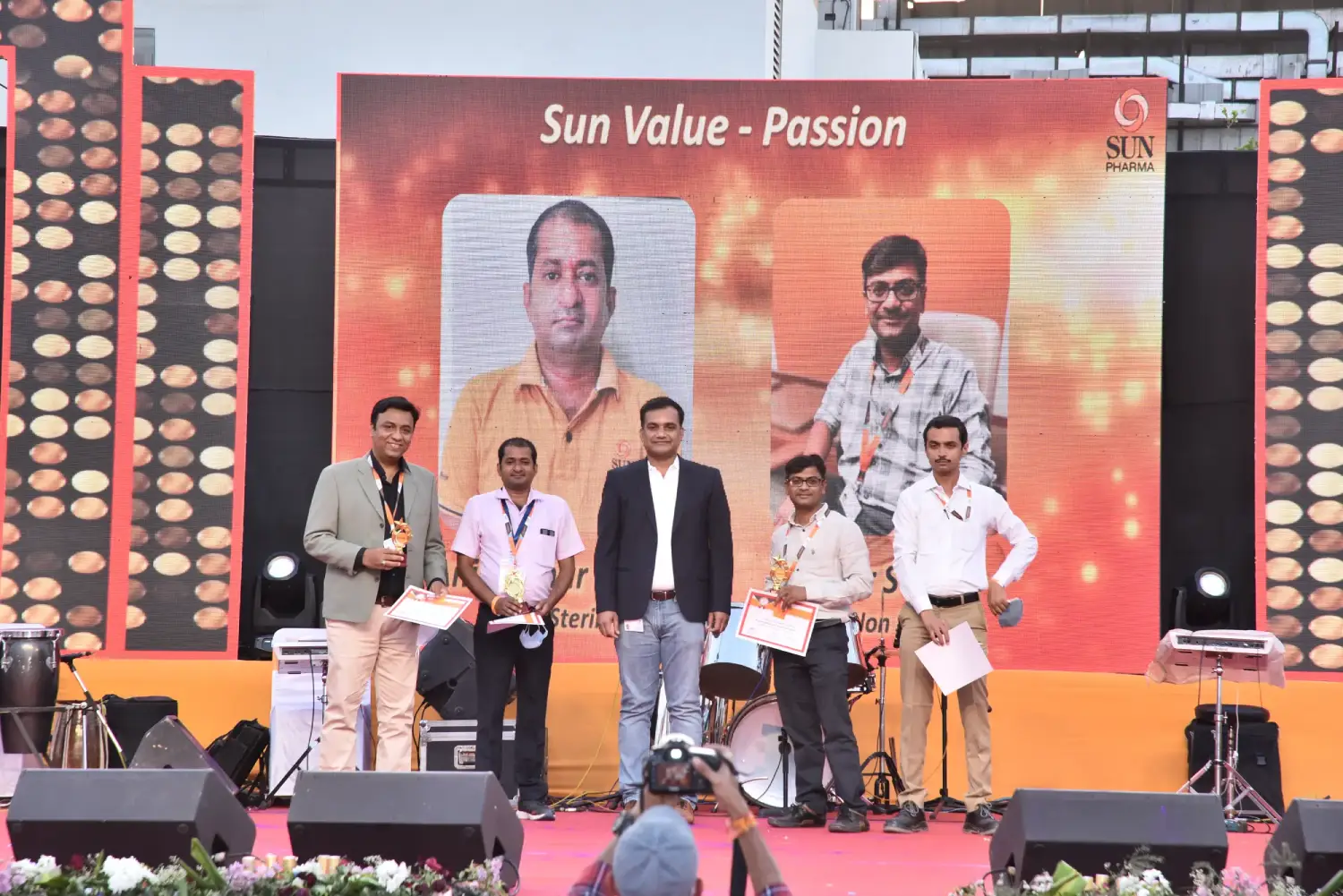 Man and woman speaking on stage at night with blue lighting